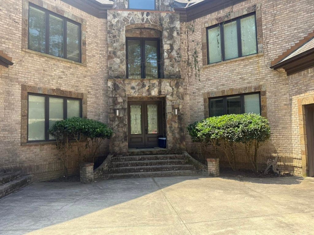 Large brick home with neatly trimmed hedges flanking the entrance